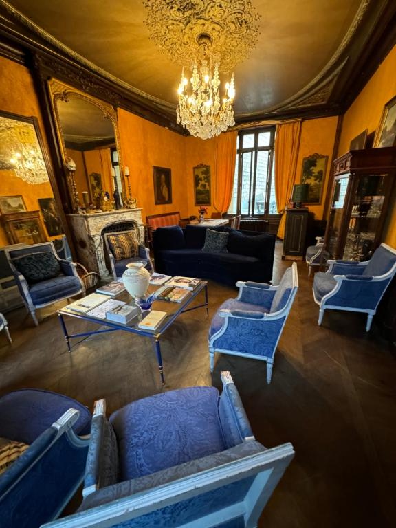 Elle comprend un salon doté d'un mobilier bleu et d'un lustre. dans l'établissement Belle Maison Laonnoise d'Antan, à Laon