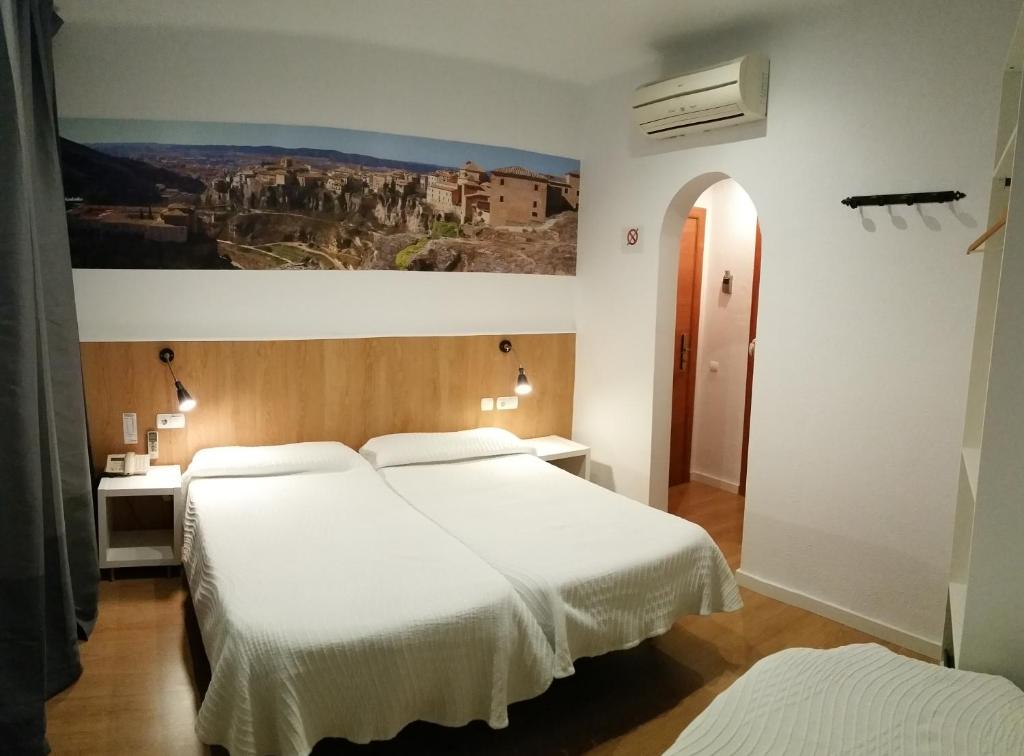 a bedroom with two beds and a painting on the wall at Hostal Restaurante Cornella in Cornellà de Llobregat