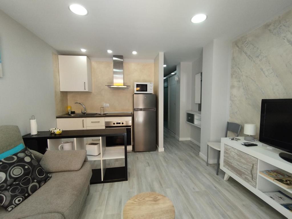 a living room with a couch and a kitchen at Arenas 50, 100 mt d playa ingles in Playa del Ingles