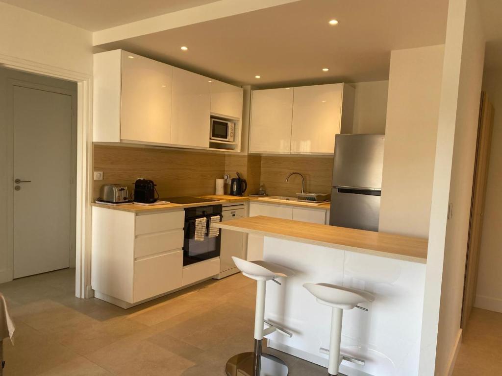 une cuisine avec des armoires blanches et des appareils en acier inoxydable dans l'établissement F2 Centre DEAUVILLE Lit 180 Parking gratuit, à Deauville