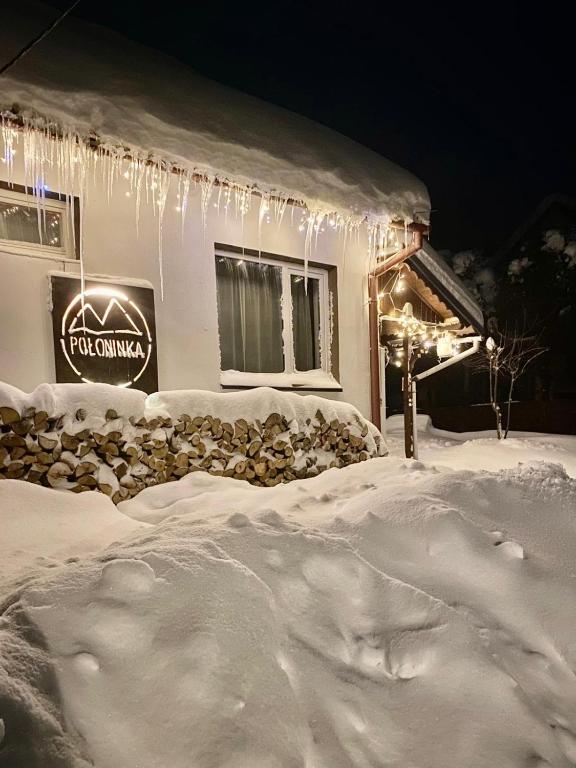 a building covered in snow with icicles and a sign at Połoninka Pokoje in Ustrzyki Górne
