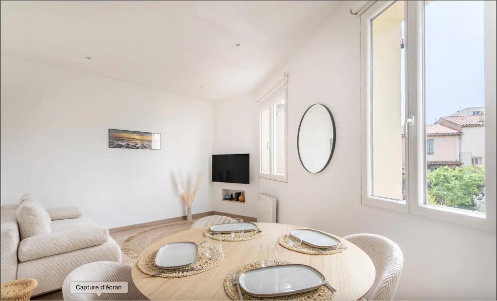 - un salon blanc avec une table et une chaise dans l'établissement Vivez une expérience méditerranéenne dans cet appartement confortable, à La Seyne-sur-Mer