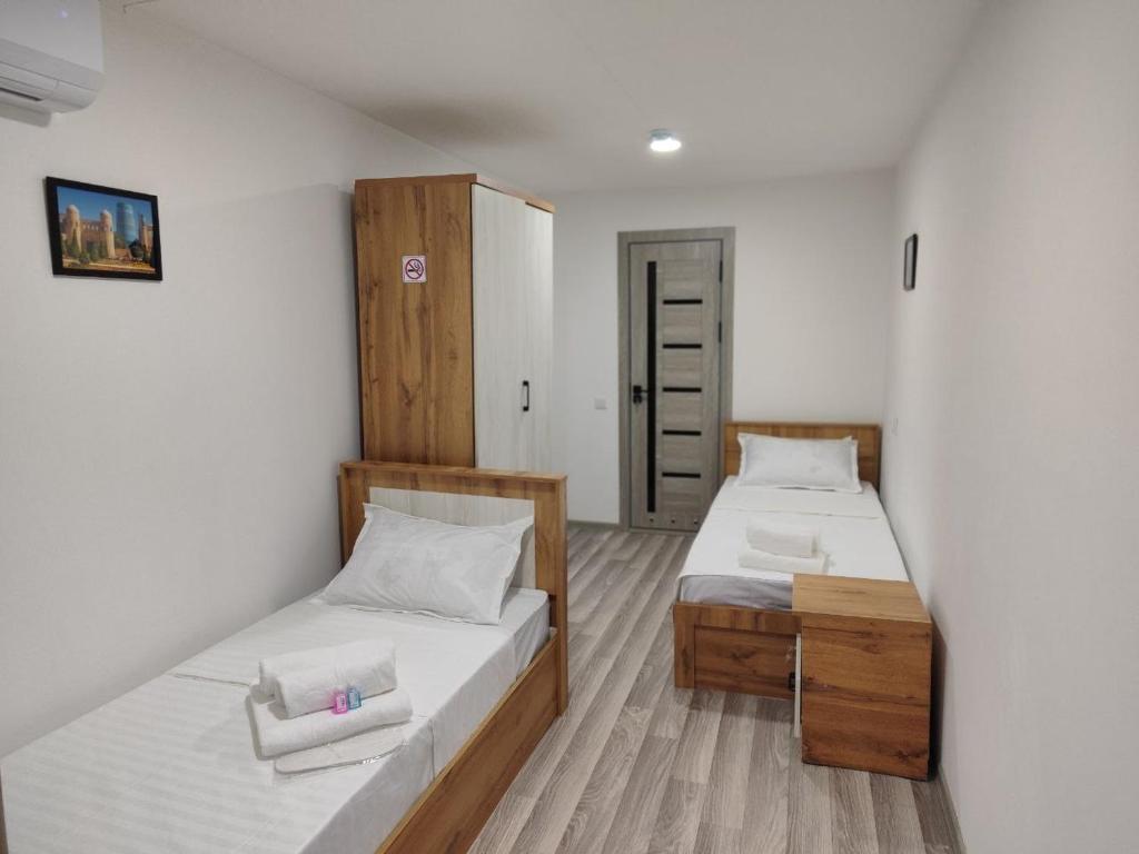 a bedroom with two beds and a cabinet at The RISE HST in Tashkent