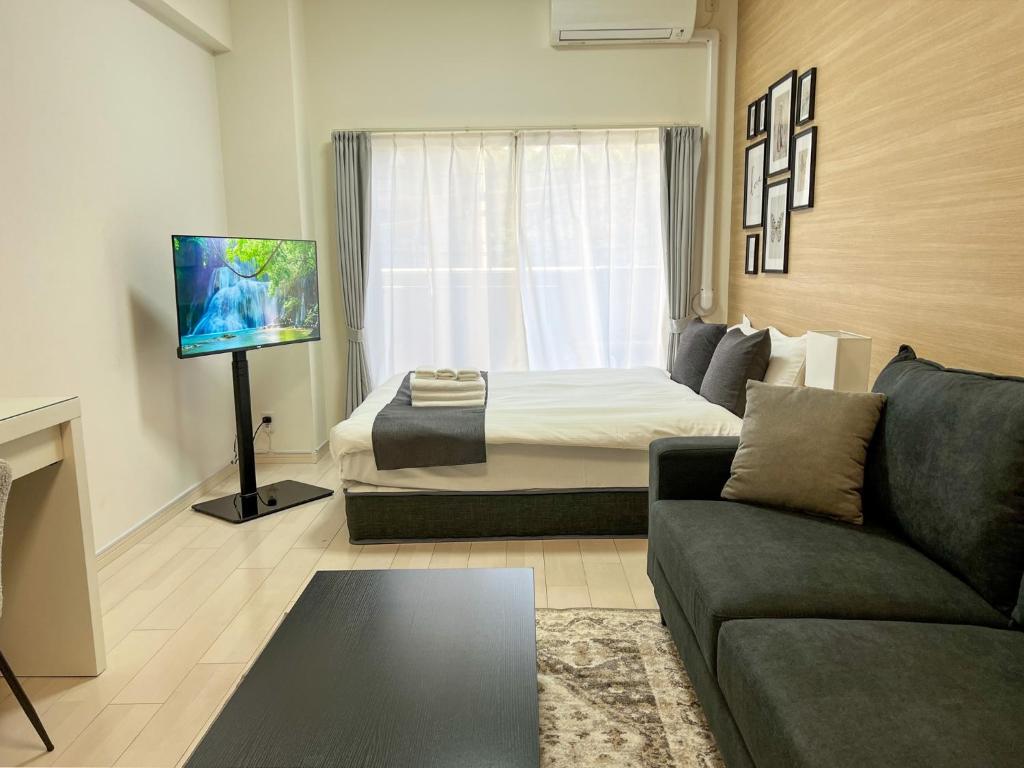 Zimmer mit einem Bett, einem Sofa und einem TV in der Unterkunft Lion Heiwa Odori - Vacation STAY 18059 in Hiroshima