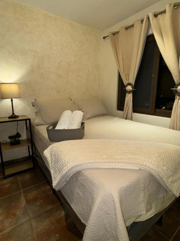 a bedroom with a bed with white sheets and a window at Suite Boutique #5 Antigua Guatemala in San Pedro Las Huertas
