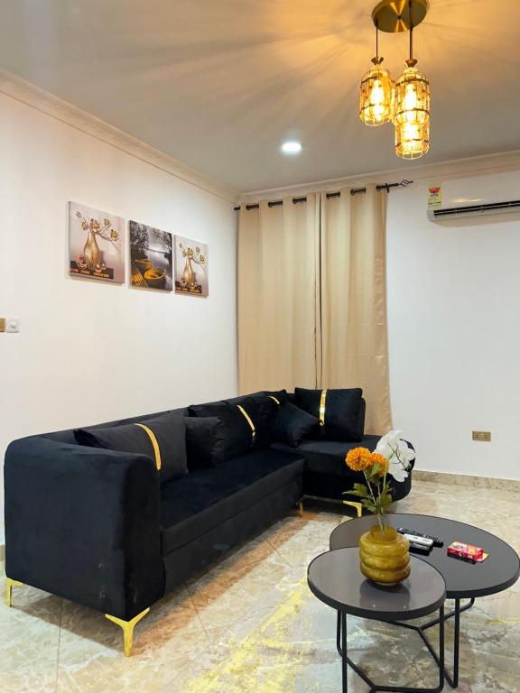 een woonkamer met een zwarte bank en een tafel bij Luxury 1bedroom apartment in Accra