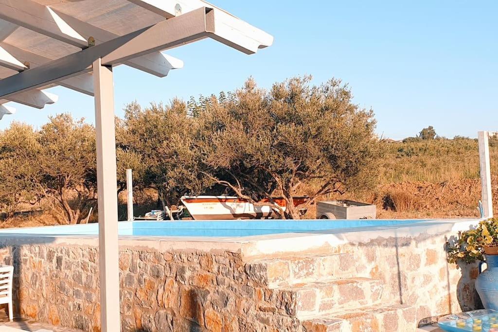 a swimming pool with a stone wall and an umbrella at Villa Kaliopi Kavros in Dhrámia