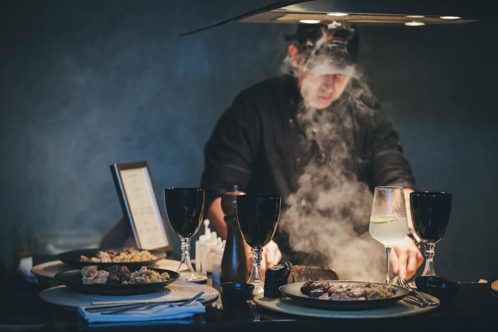 a man standing behind a table with plates of food at The Charlee Hotel in Medellín