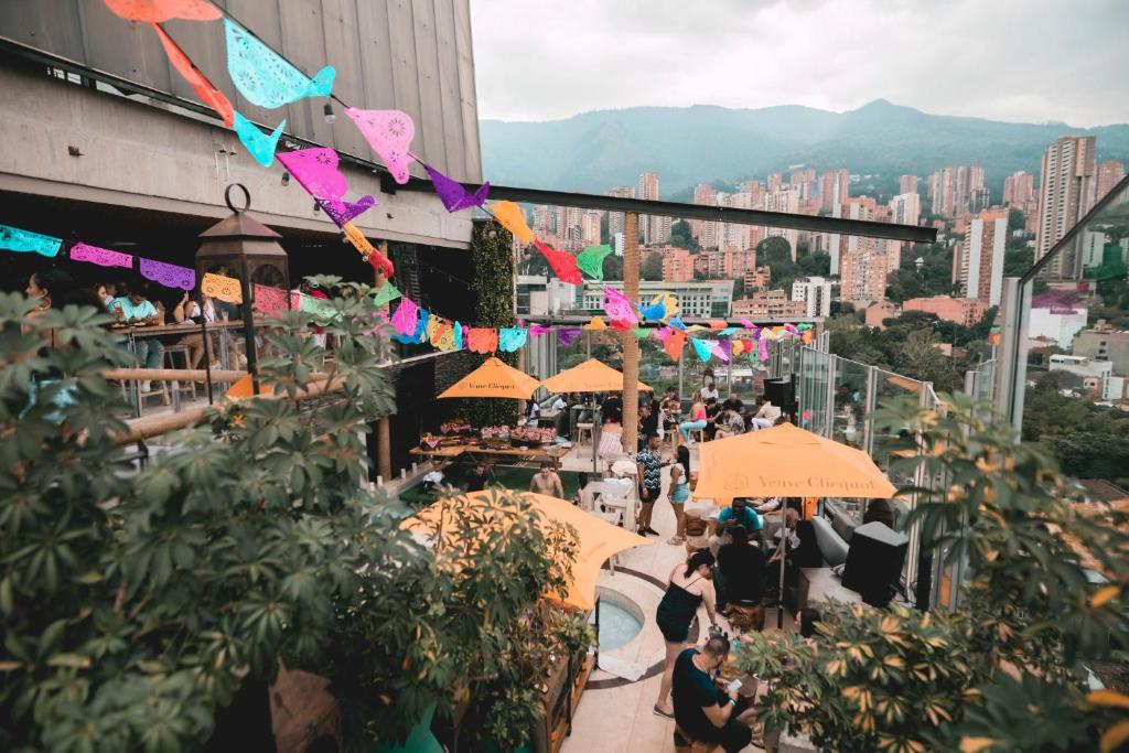 a crowd of people sitting at tables on a building with umbrellas at The Charlee Hotel in Medellín