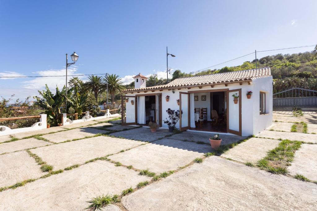 Una pequeña casa blanca con una montaña al fondo. en Casa Rural Los Barros, en Genovés