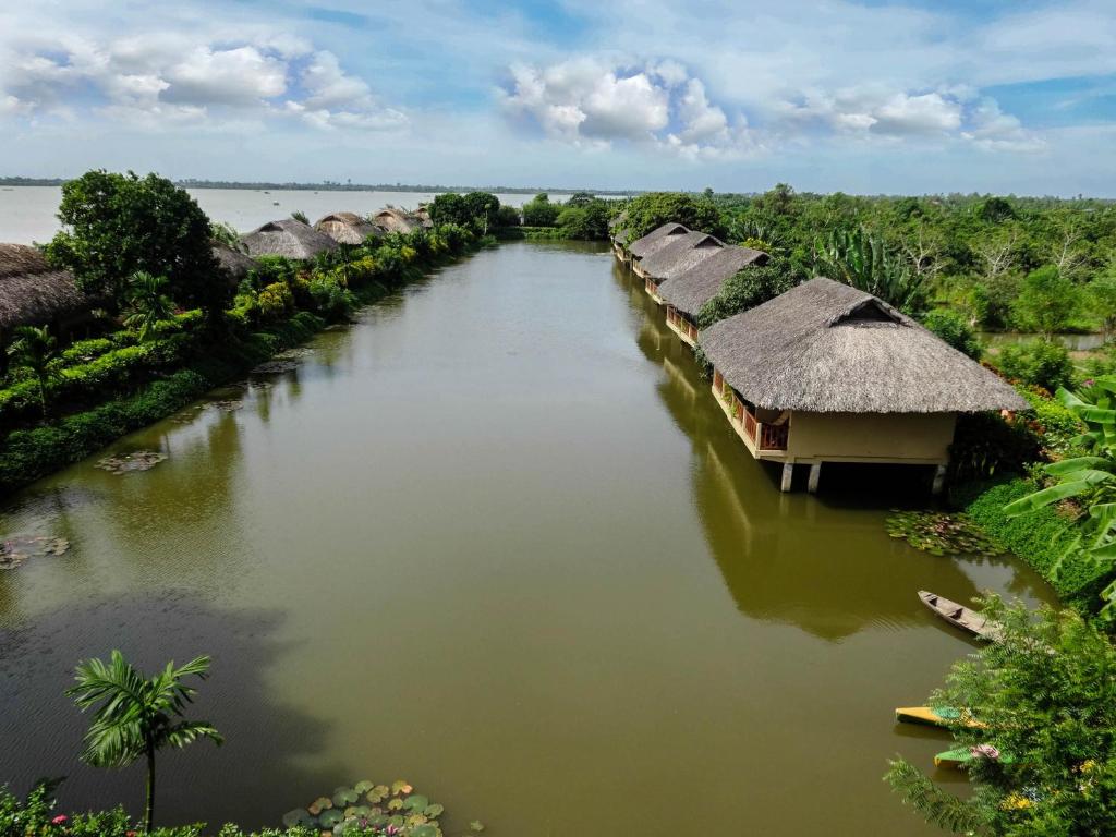 a river with a group of huts on it at Mekong Riverside Boutique Resort & Spa in Cai Be