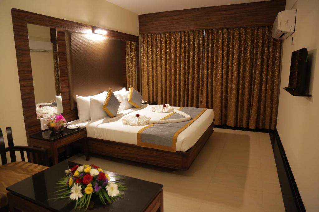 a hotel room with a bed and a table with flowers on it at Rangalaya Royal in Vellore