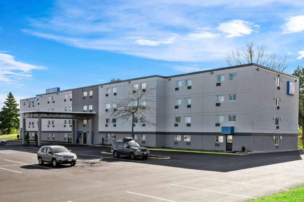 Un edificio grande con dos coches estacionados en un estacionamiento. en Motel 6-Portland, ME, en Portland