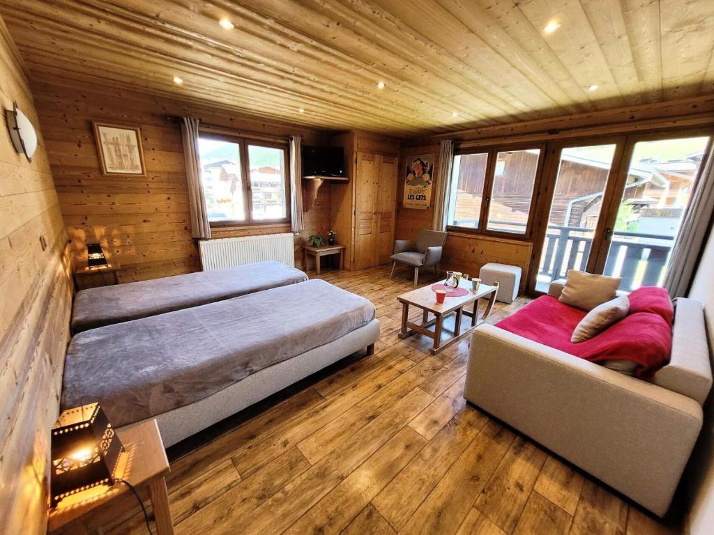 une grande chambre avec deux lits et un canapé dans l'établissement Résidence Beau Sejour - Testez le confort de louer un appartement à deux pas des remontées mécaniques ! MAE-7551, aux Gets