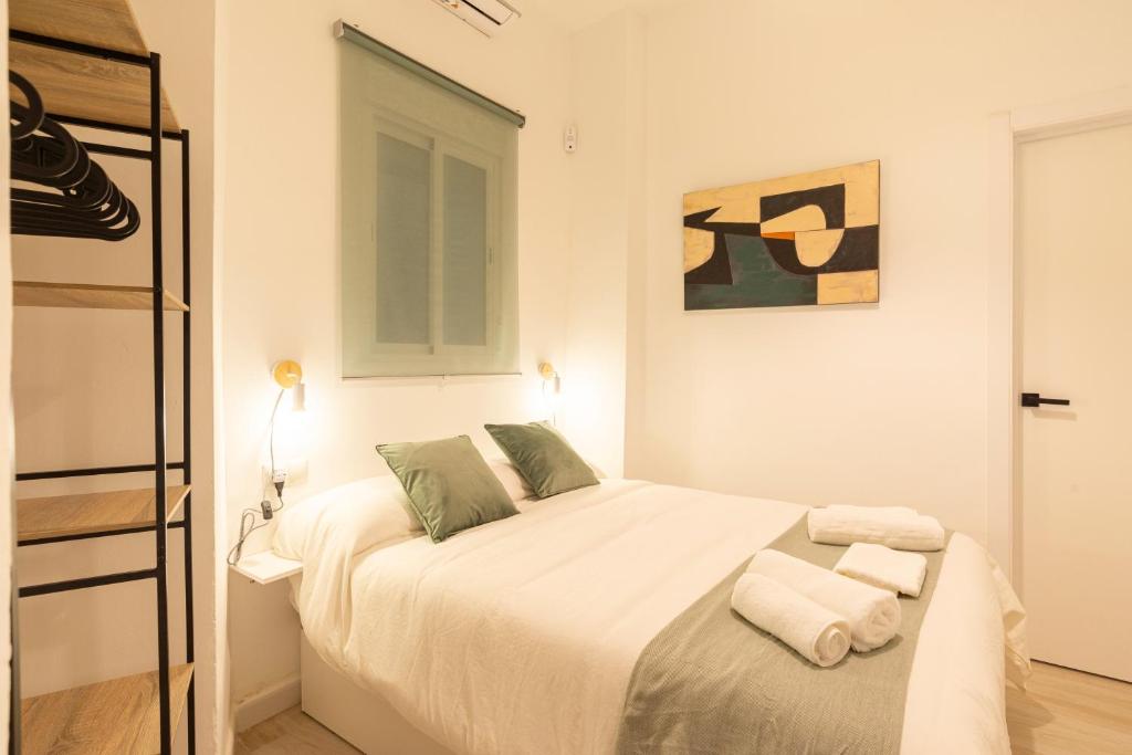 een witte slaapkamer met een bed met handdoeken erop bij Málaga Center Home in Málaga