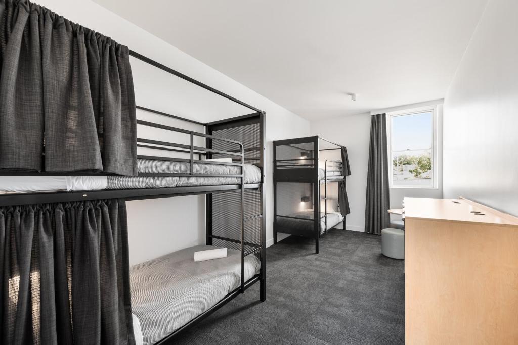 a dorm room with two bunk beds and a desk at YHA Sydney Harbour in Sydney