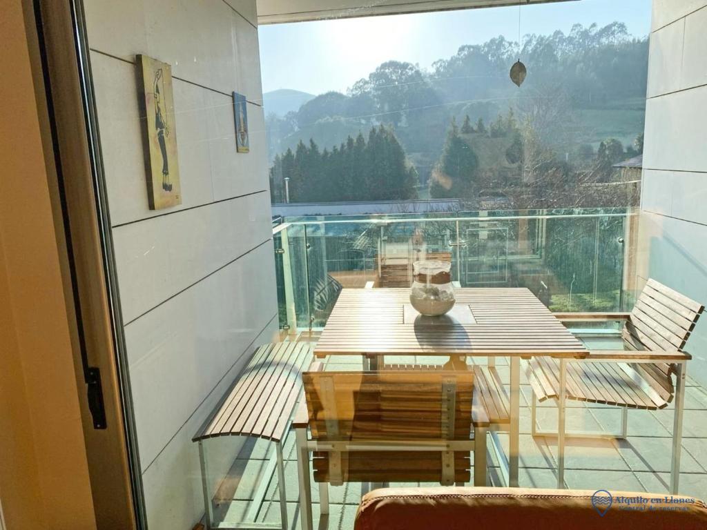 a balcony with a wooden table and a view at Casa Olmo apartamento en LLanes in Llanes