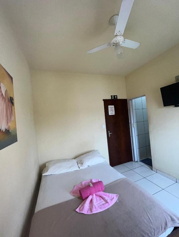 a bedroom with a bed with pink sheets and a fan at Hotel Thalita in Formiga