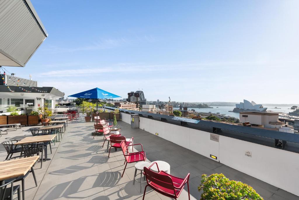 a row of tables and chairs on a patio with the water at YHA Sydney Harbour in Sydney