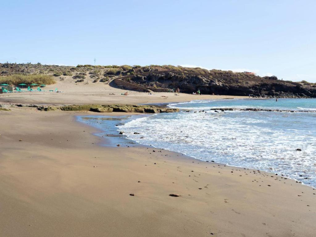 a beach with people walking on the sand and the water at Live Abades Playa y terraza in Abades