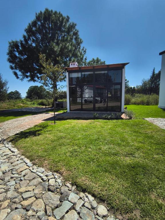 a building with a window on a grass field at Cabañas pareja Tapalpa LUNA AZUL in Tapalpa