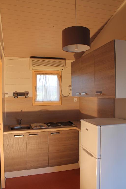 a kitchen with wooden cabinets and a white refrigerator at Le Hameau des Genets in Montlaur