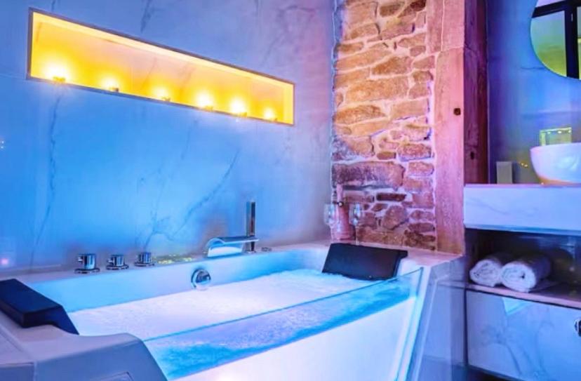 La salle de bains est pourvue d'une baignoire et d'un mur en pierre. dans l'établissement Cosy Love, à Saint-Alban-de-Roche