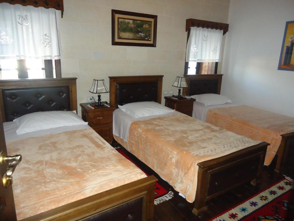 a bedroom with two beds and two windows at Hotel Klea in Berat
