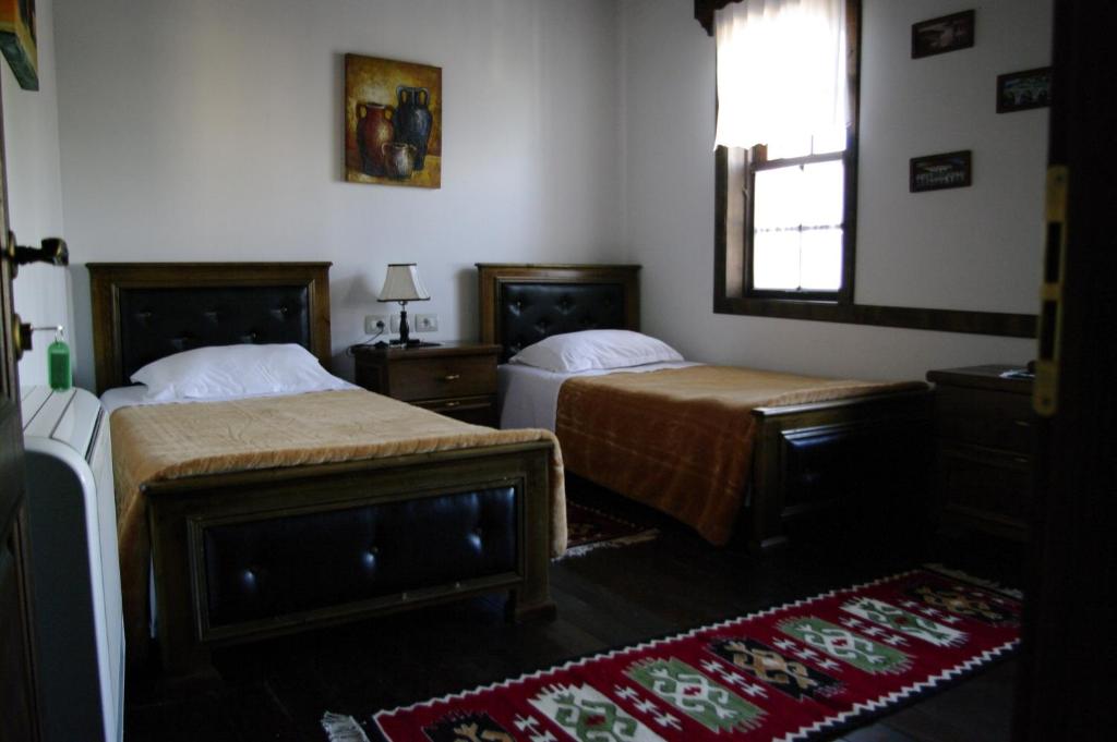 a bedroom with two beds and a window and a rug at Hotel Klea in Berat