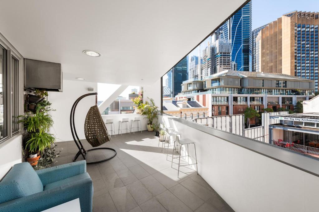 an apartment balcony with a blue couch and chairs at YHA Sydney Harbour in Sydney