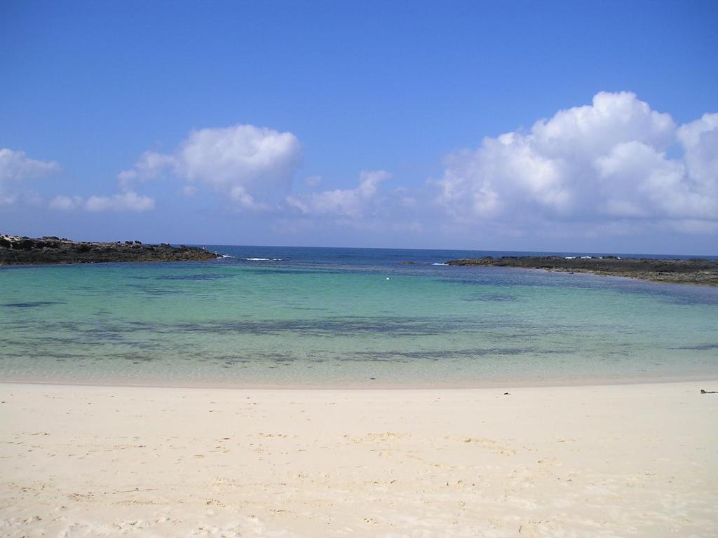 a beach with the ocean and blue water at Apartamento Cotillo Playa in El Cotillo
