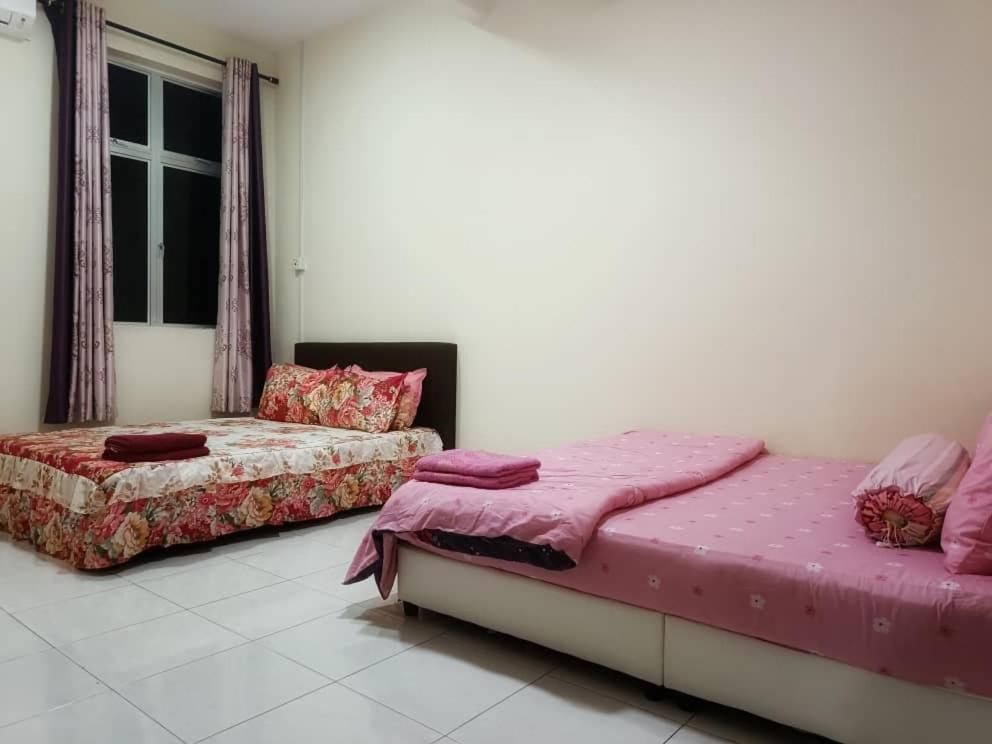 two beds in a room with pink sheets at Chek Embun Homestay in Padang Besar