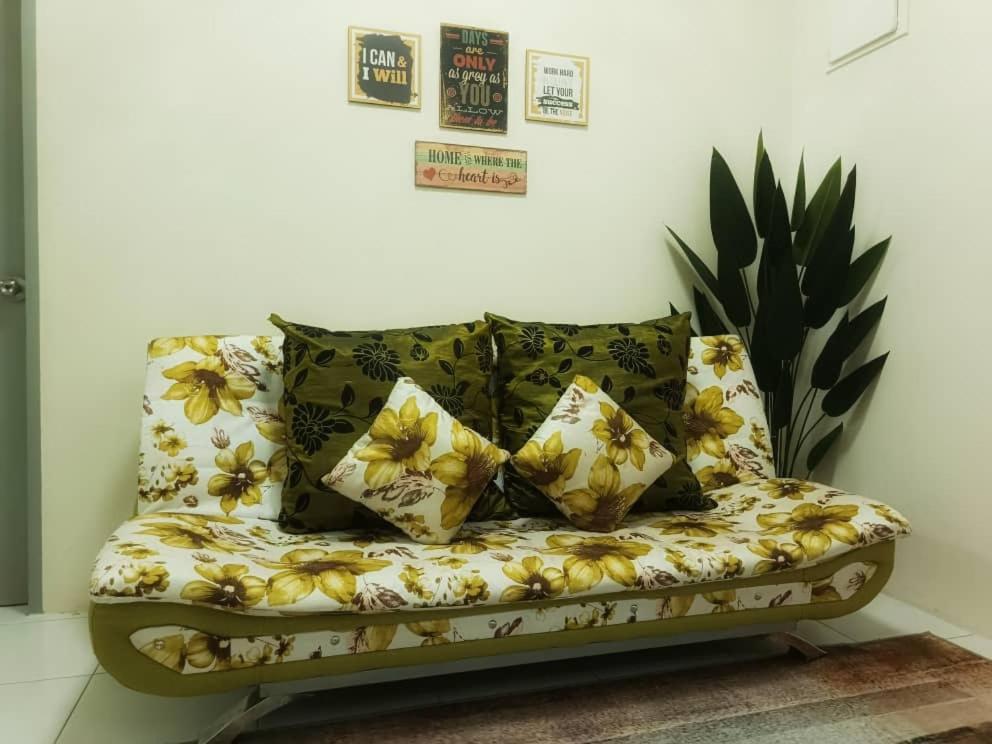 a couch with yellow flowers on it in a room at Chek Embun Homestay in Padang Besar