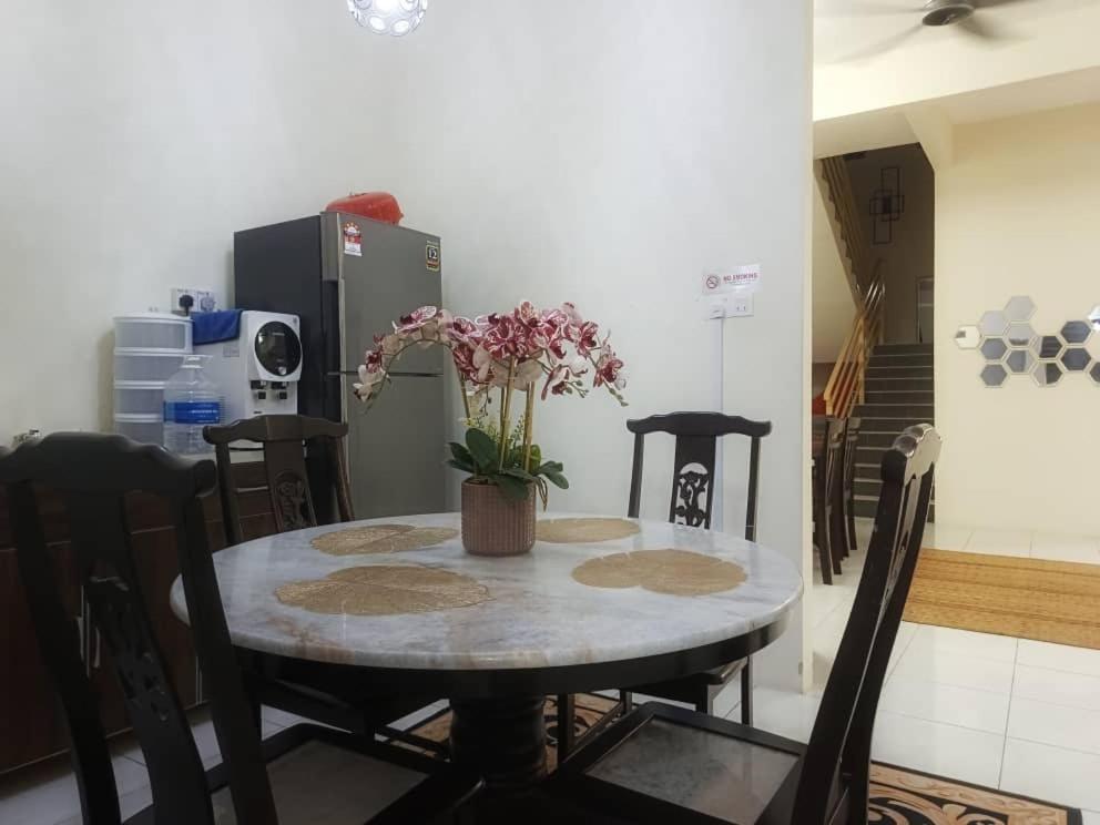 a dining room table with a vase of flowers on it at Chek Embun Homestay in Padang Besar