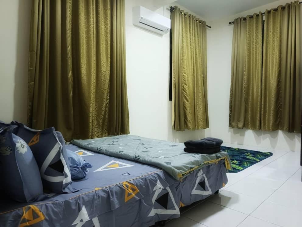a bed in a room with green curtains at Chek Embun Homestay in Padang Besar