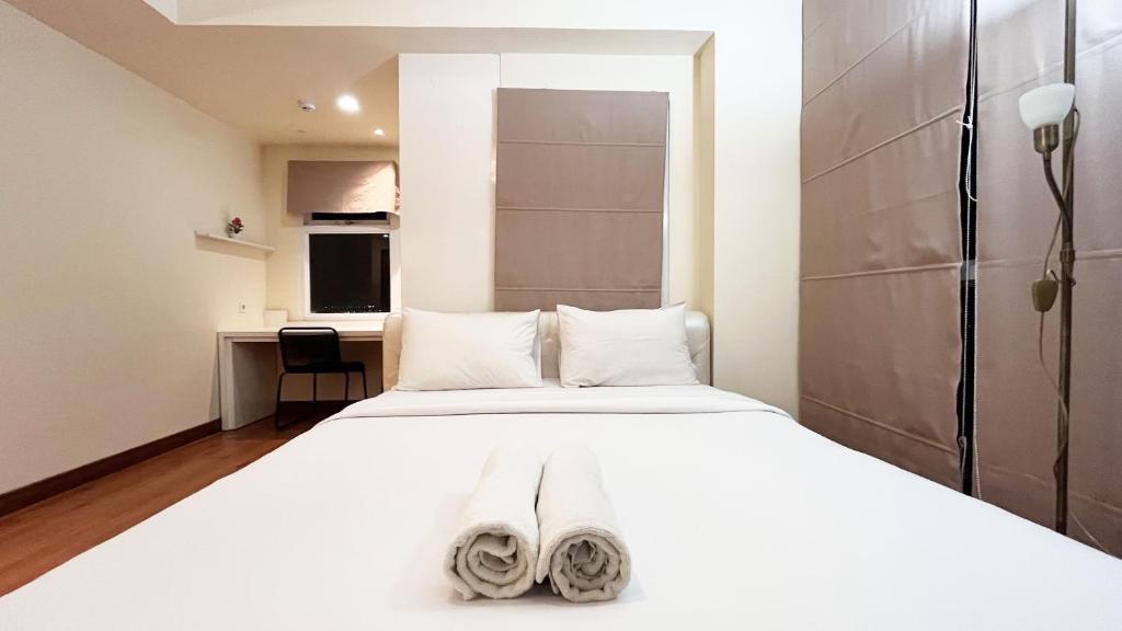 a bedroom with a white bed with towels on it at Stylish Studio Room at Apartment Vida View Makassar By Travelio in Pampang