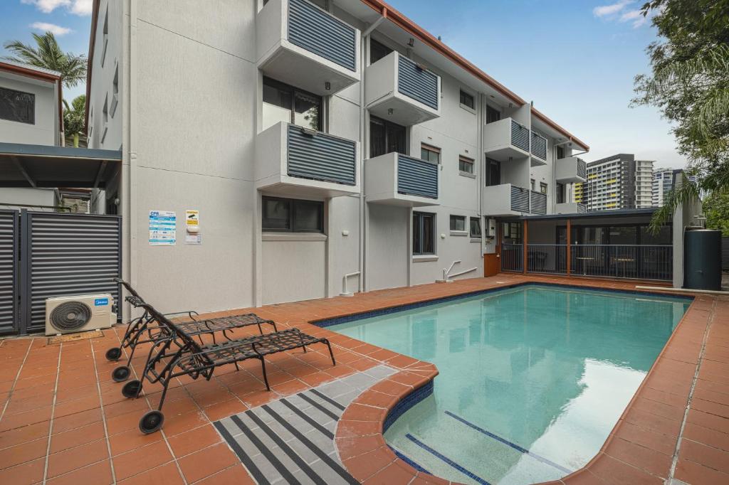 a swimming pool with a bench next to a building at Asraport Motel in Brisbane