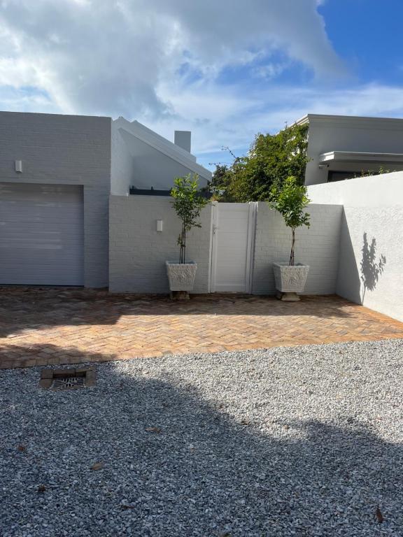 Una casa con dos árboles en macetas delante de ella. en On Musson, en Hermanus