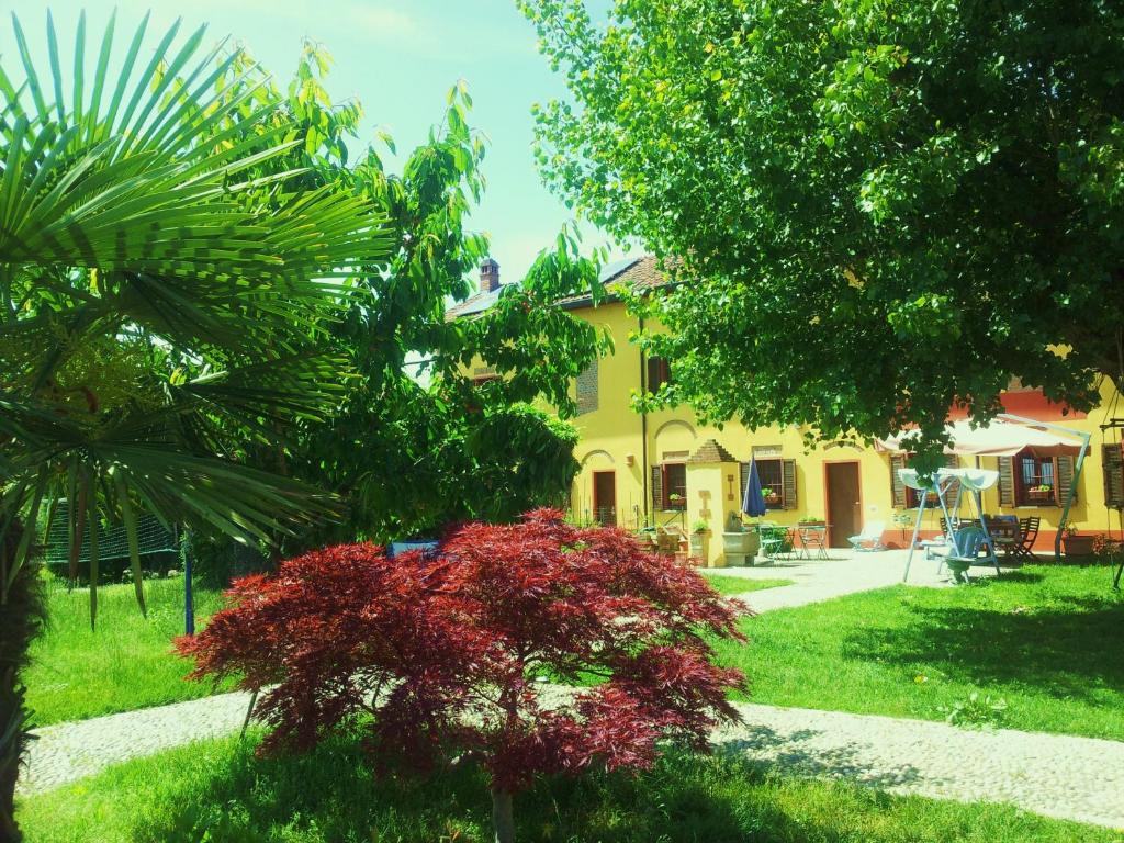 a garden with red plants and a yellow house at B&B Il Pioppo E La Fonte in Castello d'Agogna