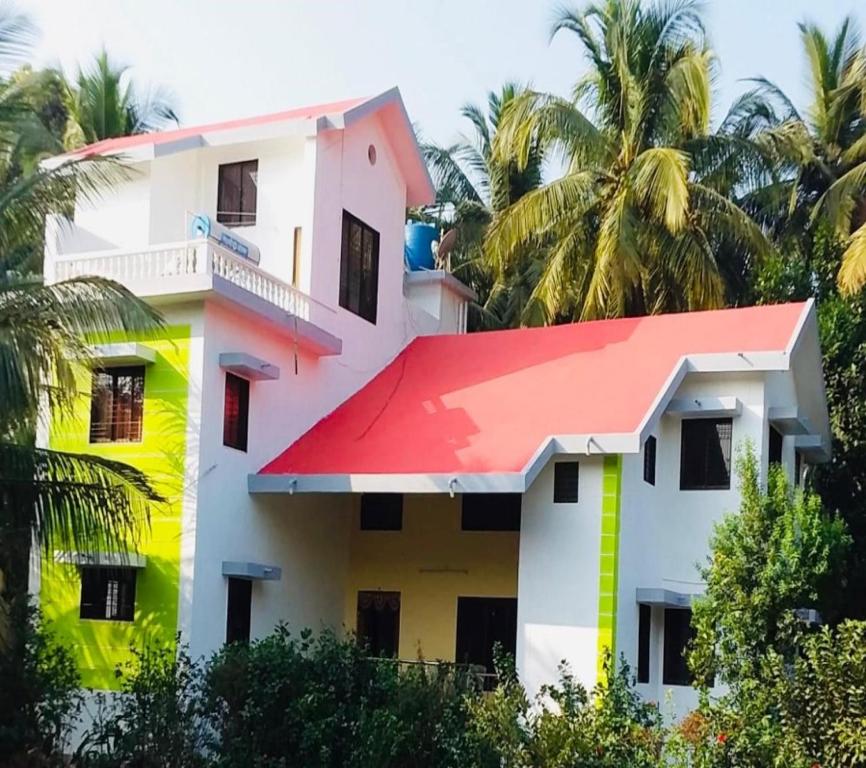 una casa con techo rojo y palmeras en Yogiraj HomeStay - Tarkarli-Malvan, en Malvan