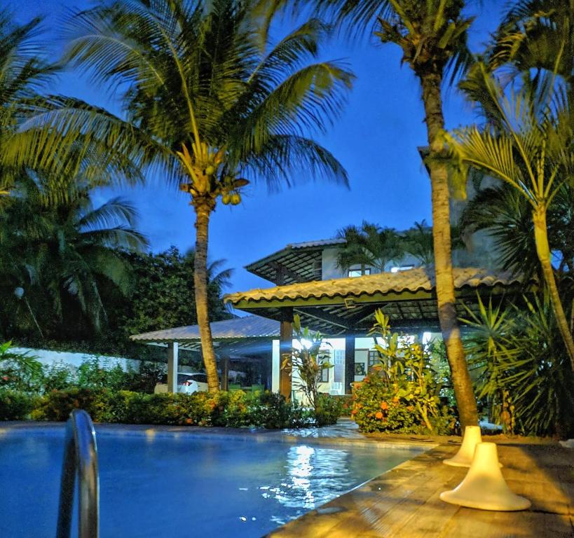 a resort with palm trees and a swimming pool at Casa 4 quartos em Guarajuba, excelente localização! 200m da praia! in Camacari
