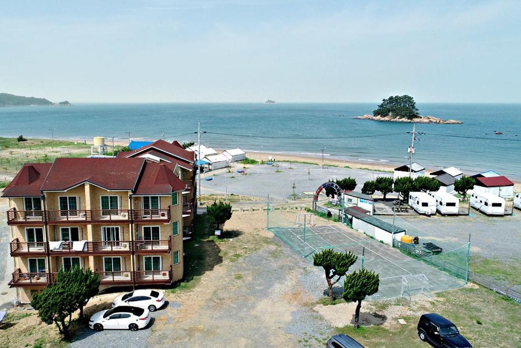 a building with cars parked in a parking lot next to the ocean at Hakahmpo Haneul Pension in Taean