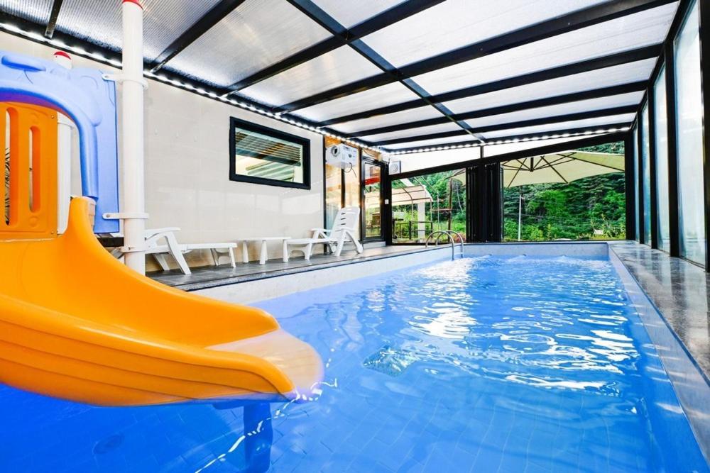 a swimming pool with a slide in a house at Vine family and kids four season pool villa in Gapyeong