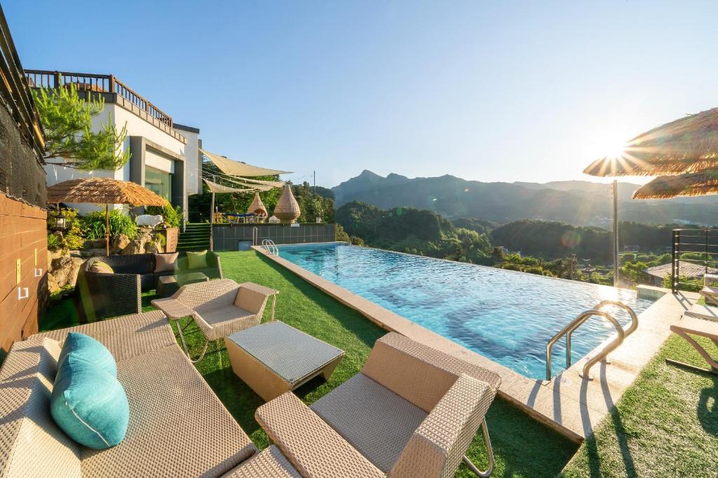 a swimming pool with chairs and an umbrella on a house at Gapyeong Bobo Dog Pool Villa in Gapyeong