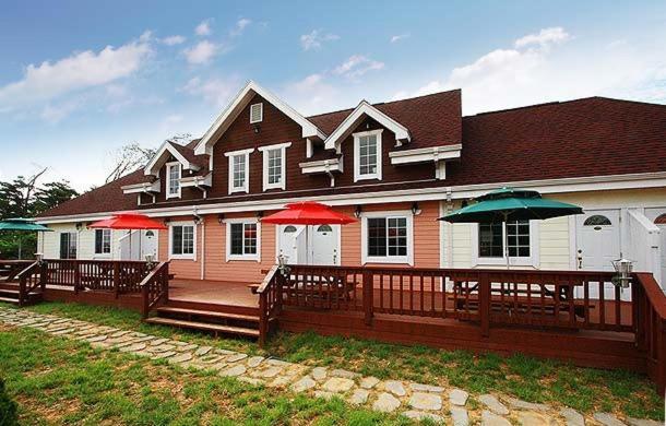 a house with red and green umbrellas on a deck at Namdangrodem Pension in Hwangdo