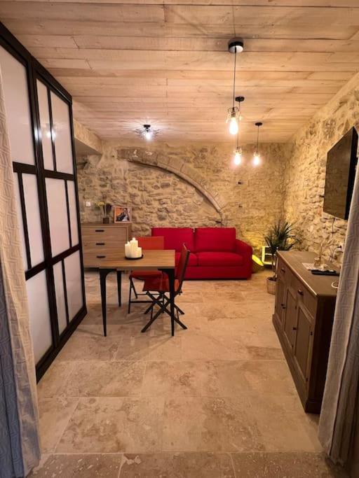 un salon avec un canapé rouge et une table dans l'établissement Grand studio de charme dans une bâtisse du XVII, à LʼIsle-sur-la-Sorgue