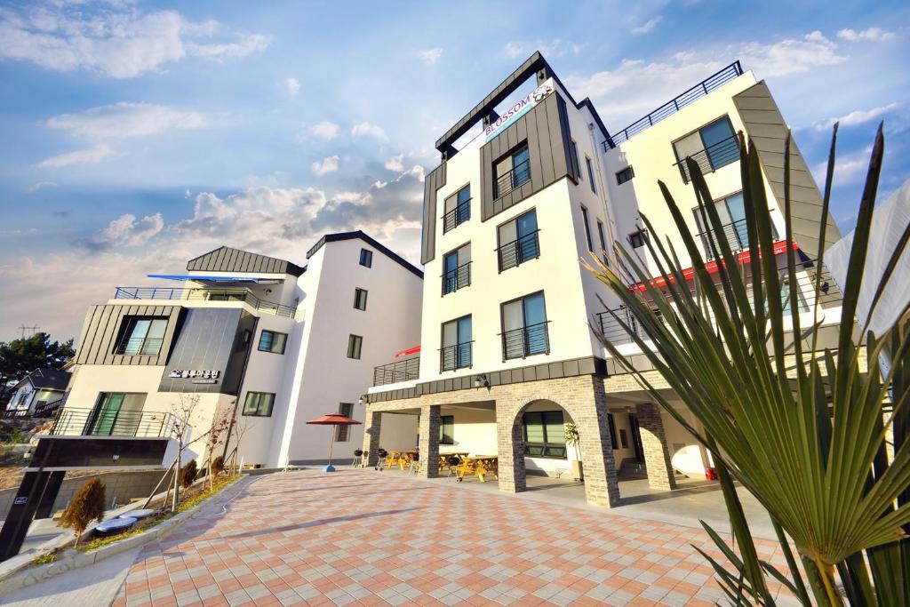 a large white building with a palm tree in front of it at Samcheok blossom pension in Samcheok