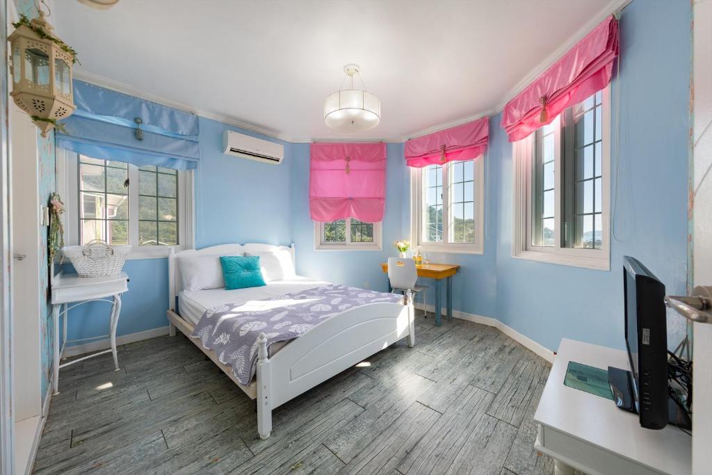 a bedroom with blue walls and a bed and a tv at Gwanghwa Concert Pension in Incheon