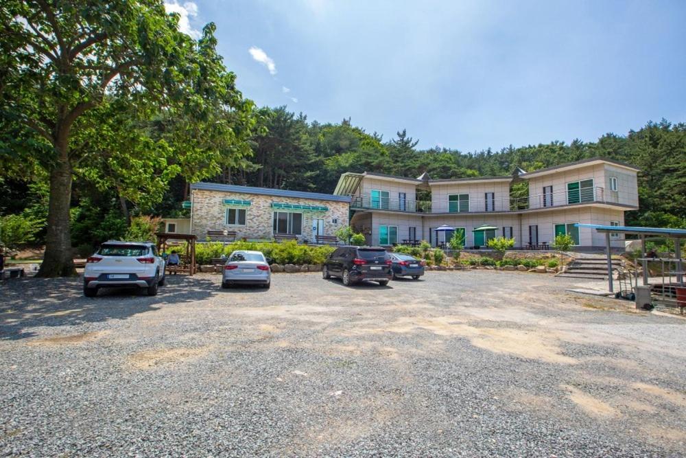 a large building with cars parked in a parking lot at Taean Scenic Pension in Taean