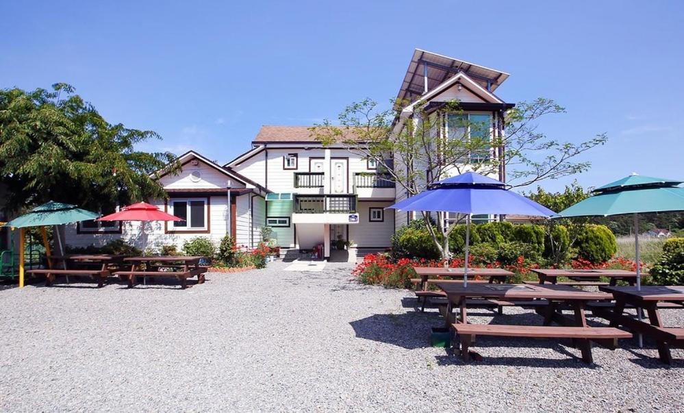 Un grupo de mesas de picnic con sombrillas frente a un edificio. en Aquapia House, en Taean